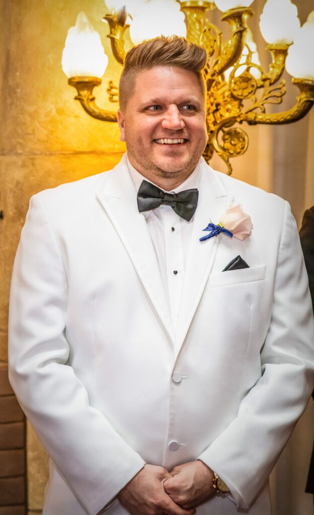 Michael smiling in his white wedding suit