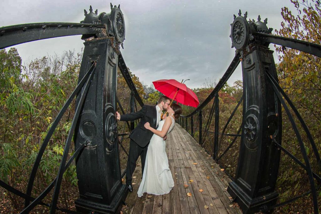 Casey and Joseph kissing under a wet umbrella