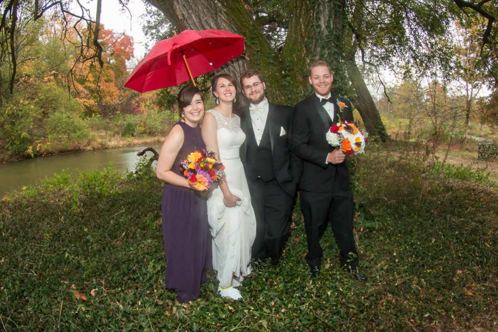 Casey and Joseph with their attendants under the cover of a tree