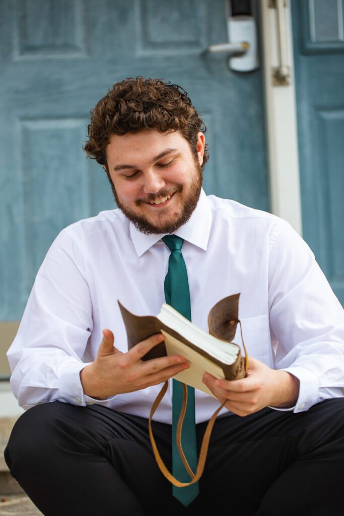A man smiling as he opens the book