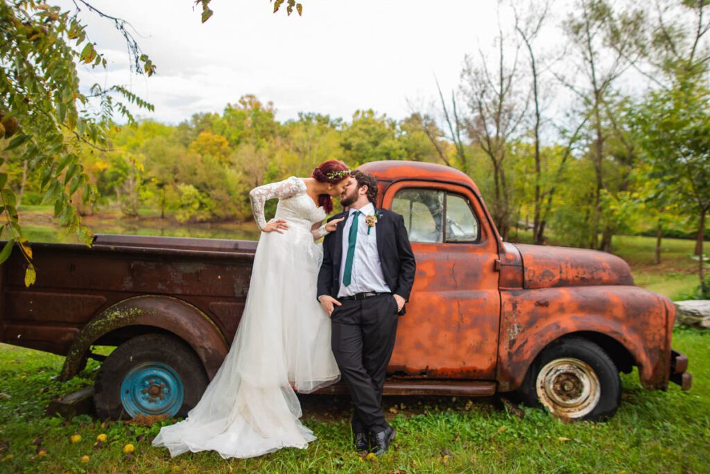Nicole and Christian kissing beside a ruined vehicle