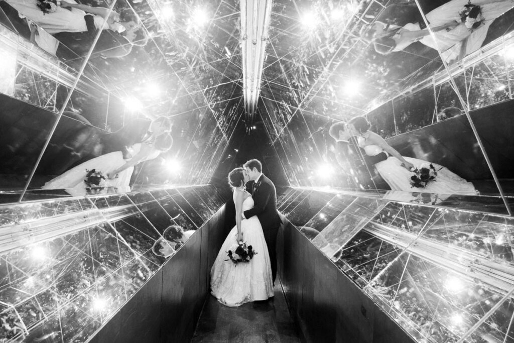 A grayscaled image of Kelsey and Nick kissing inside a mirrored hall
