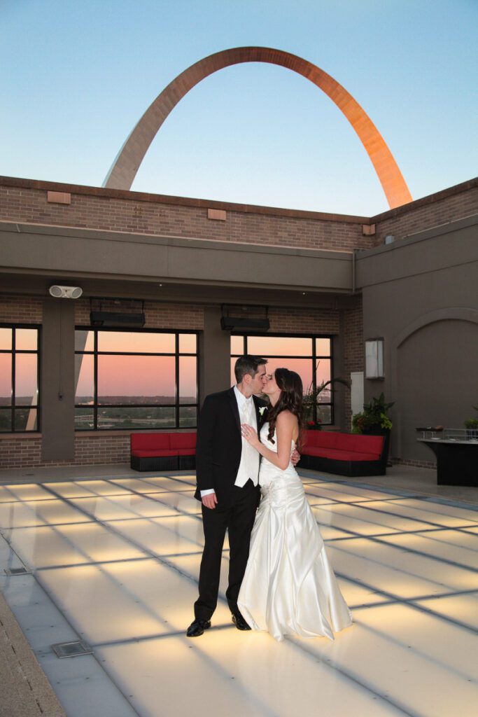 A bride and groom kissing on an open roof top