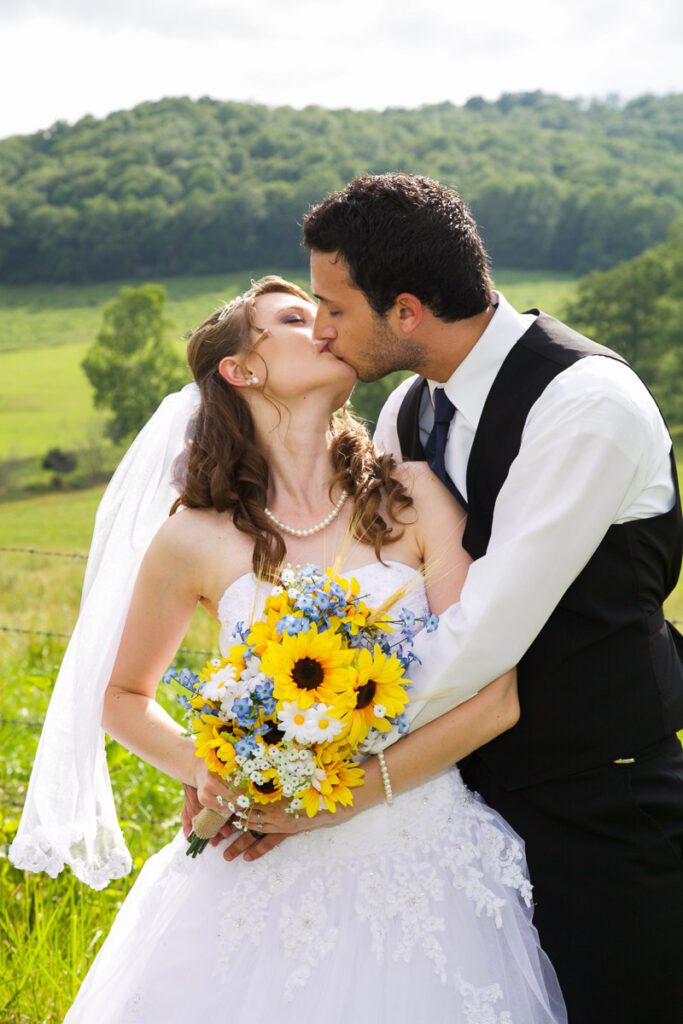 A bride and groom kissing near a countryside