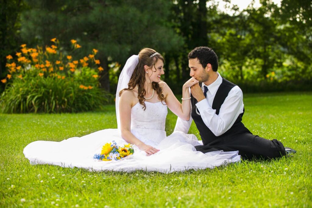 A bride and groom sitting on the grass