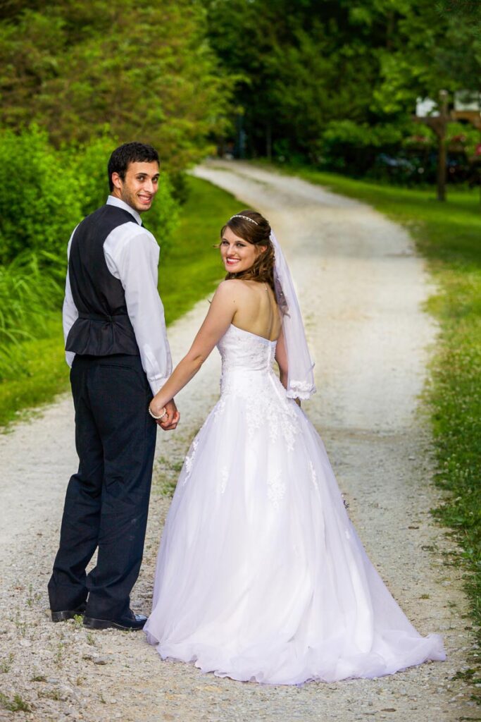 A bride and groom walking on a dirt road