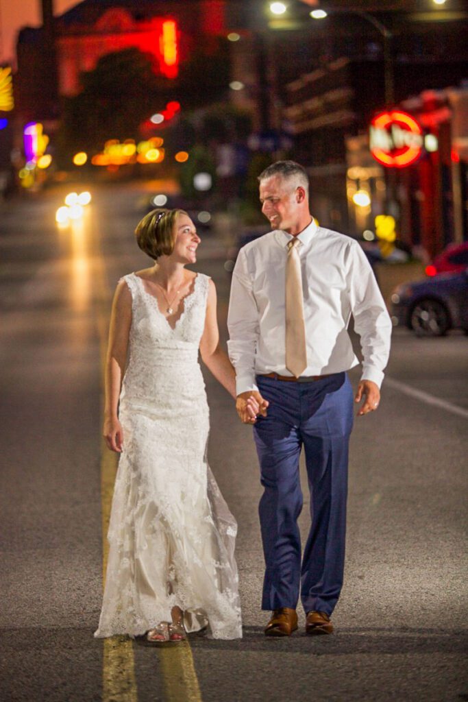 A bride and groom walking down a road at night