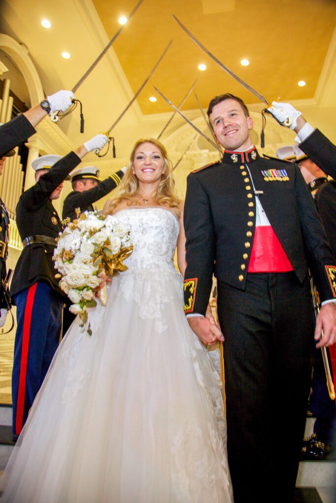 The bride and groom pass through a military salute