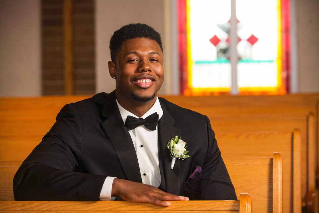 The groom sitting on a church bench