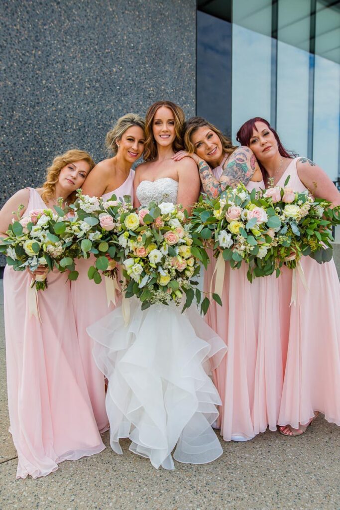 Brianna with her bridesmaids and large bouquets of flowers