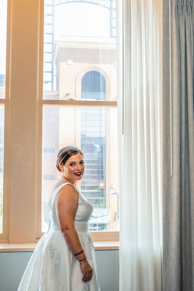 A bride smiling by the window