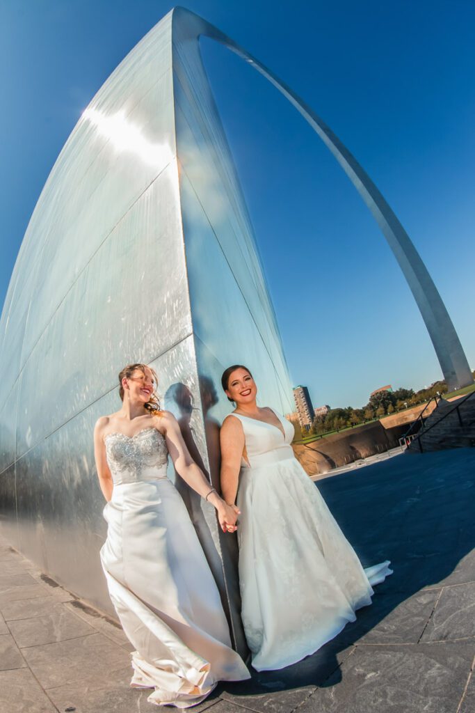 Brides holding hands at the foot of the Gateway Arch