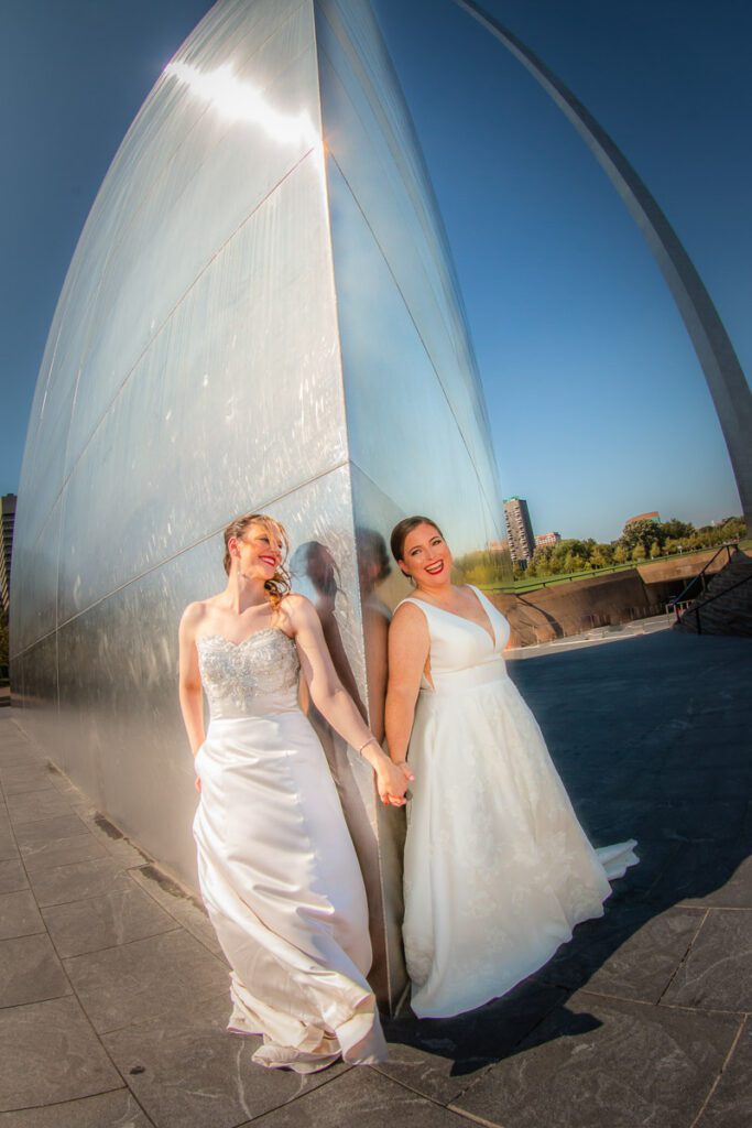 Brides holding hands at a corner of the Gateway Arch