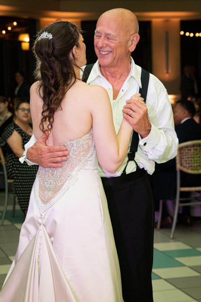 One of the brides dancing with their father