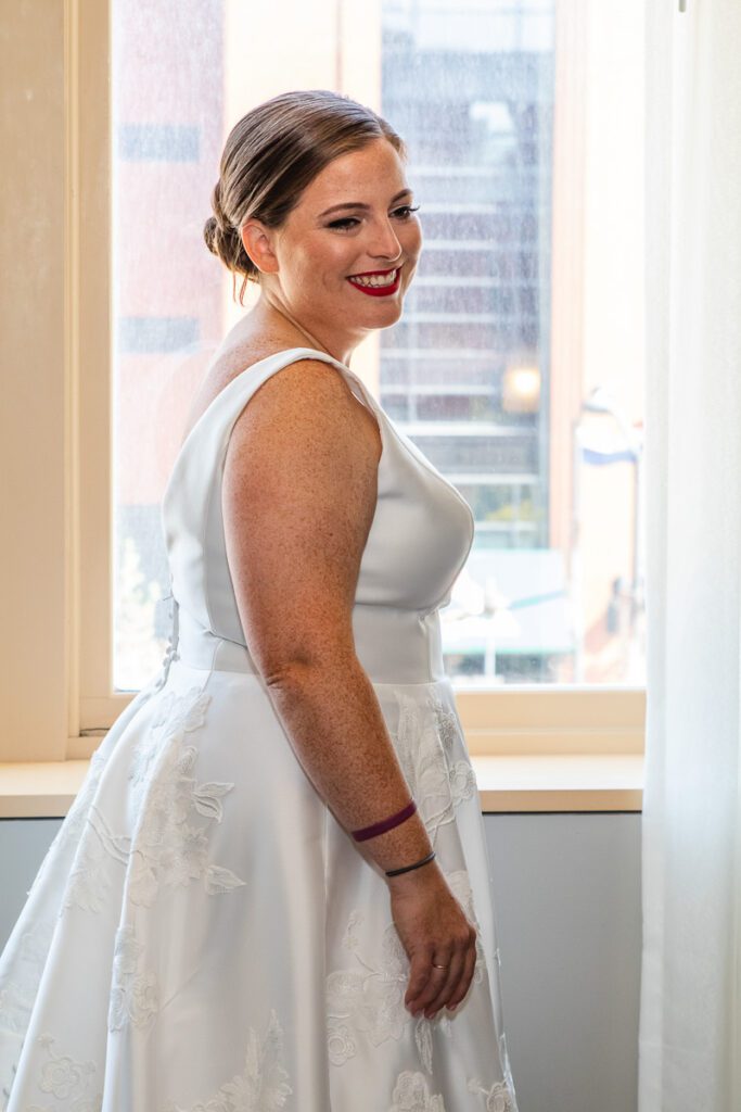 A bride standing by the window smiling