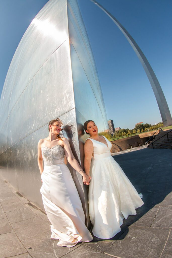 The brides holding hands at the Gateway Arch