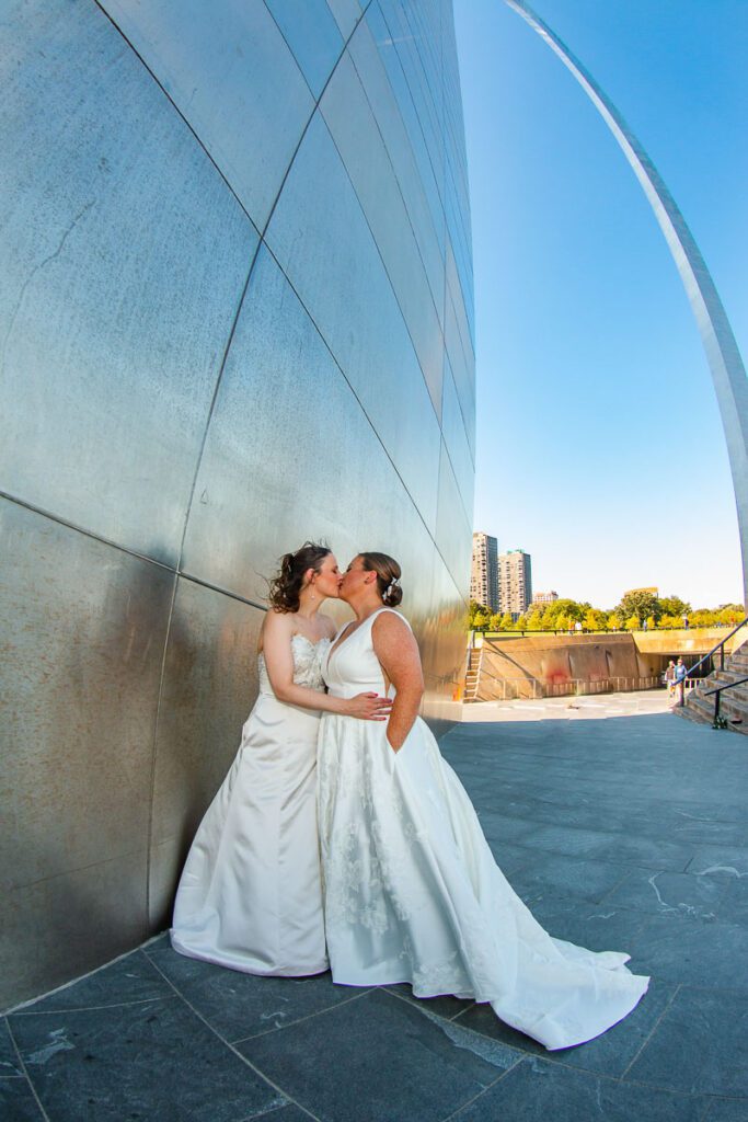 The brides kissing while holding each other close at the Gateway Arch