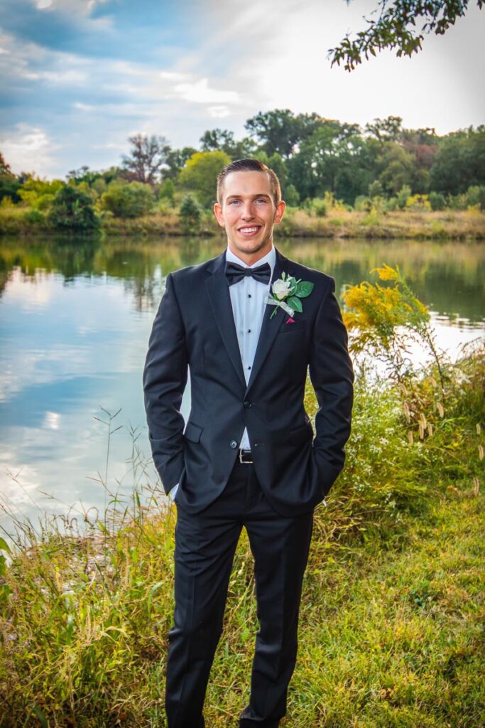 James standing in his wedding suit near the water