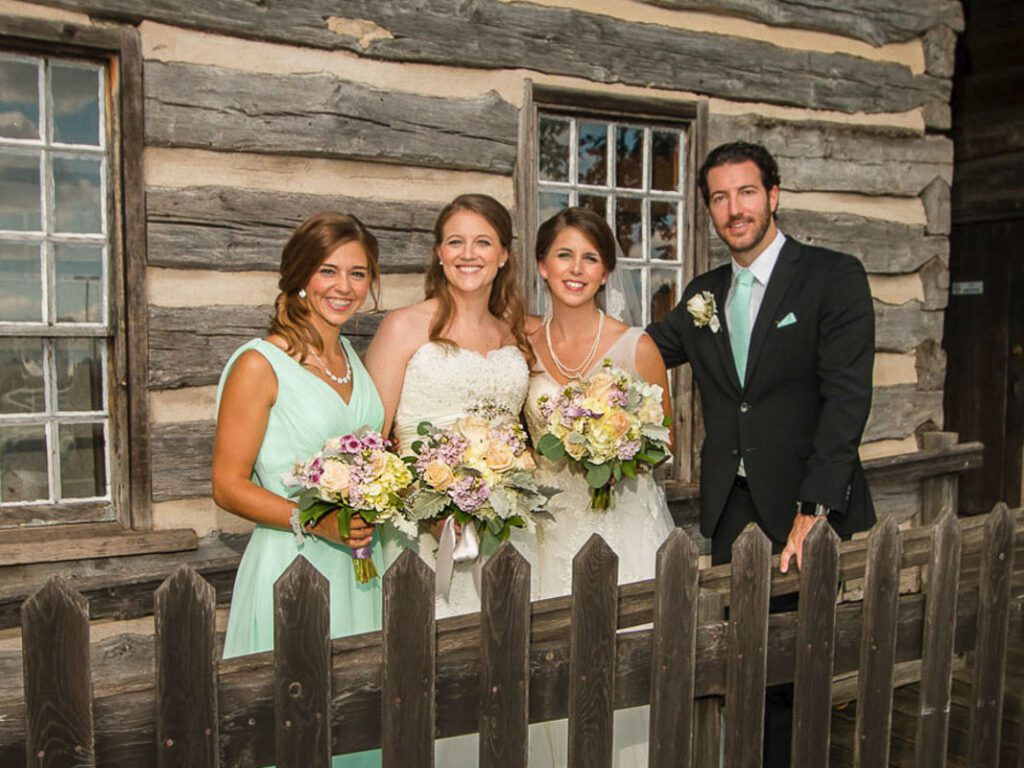 The brides and their attendants outside a wooden building