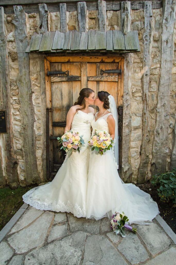 Two brides kissing each other at a door