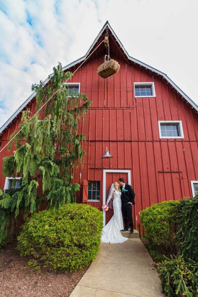 Jenna and Josh kissing outside of a red barn building