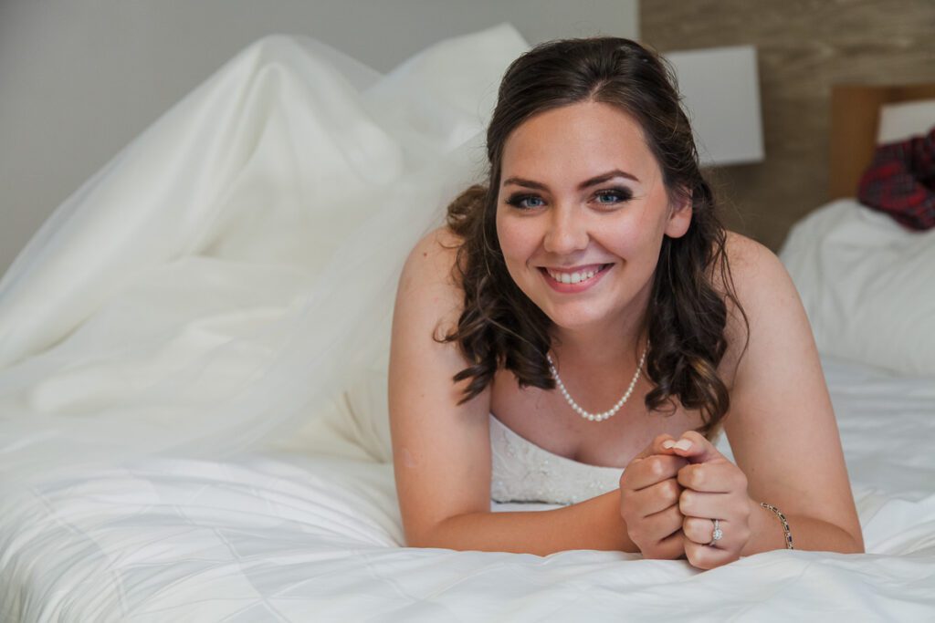 Rachel smiling in her wedding dress on bed