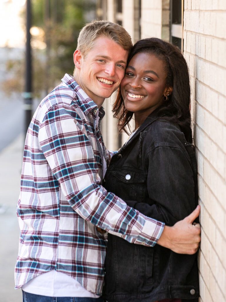 A white man and a black woman smiling while close to each other