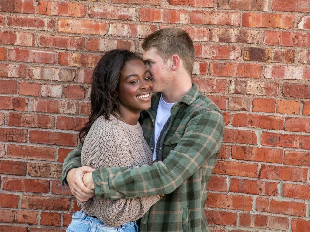 A happy couple in front of a brick wall 