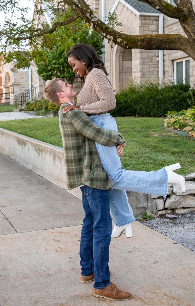 A white man lifting a black woman
