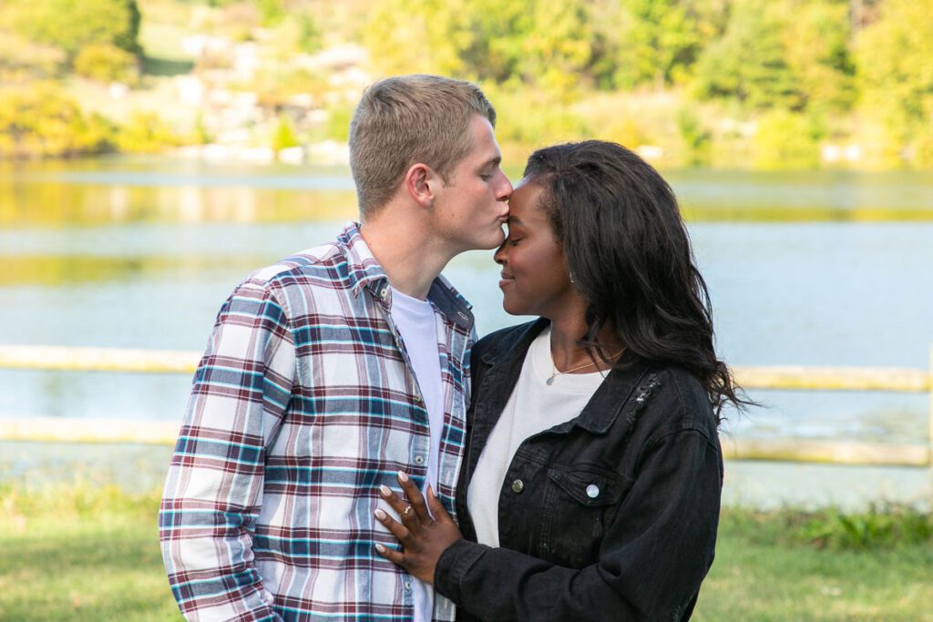 A white man kissing a black woman’s forehead