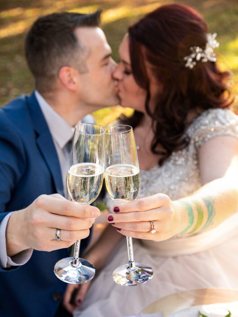 A bride and groom making a toast while kissing