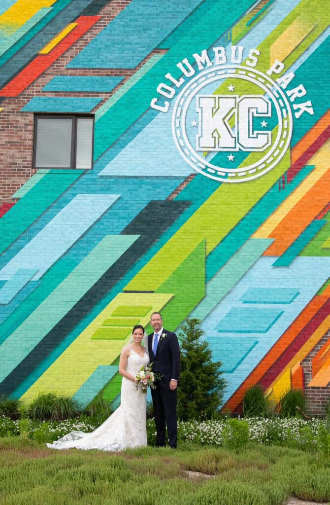 The bride and groom in front of a brick wall with a Columbus Park design