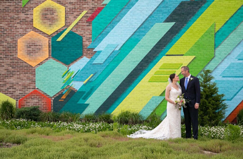 The bride and groom in front of a colorful brick wall