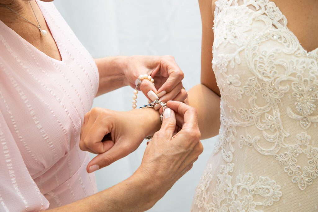 A woman helping the bride wear her jewelry