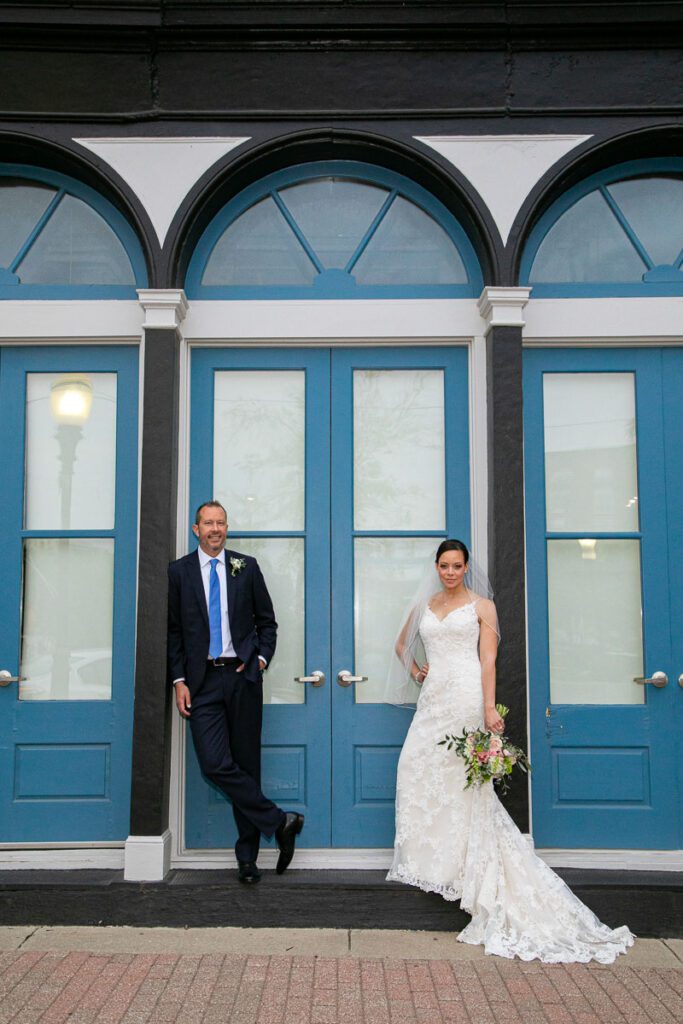A groom and the bride standing by the trims of the arched door way