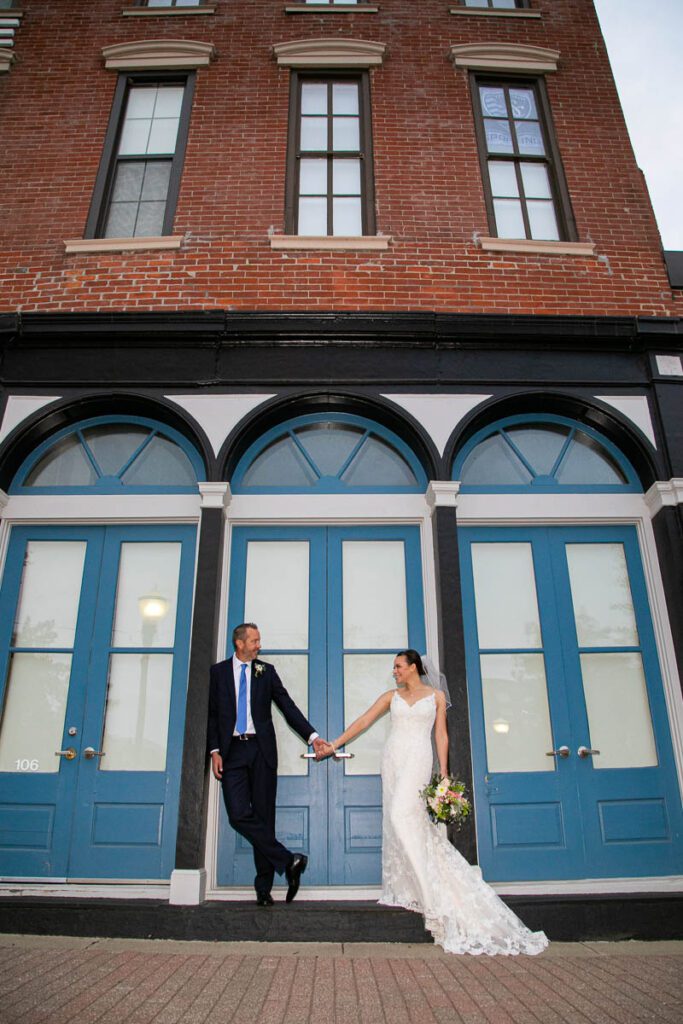 A bride and groom holding hands in front of a blue door