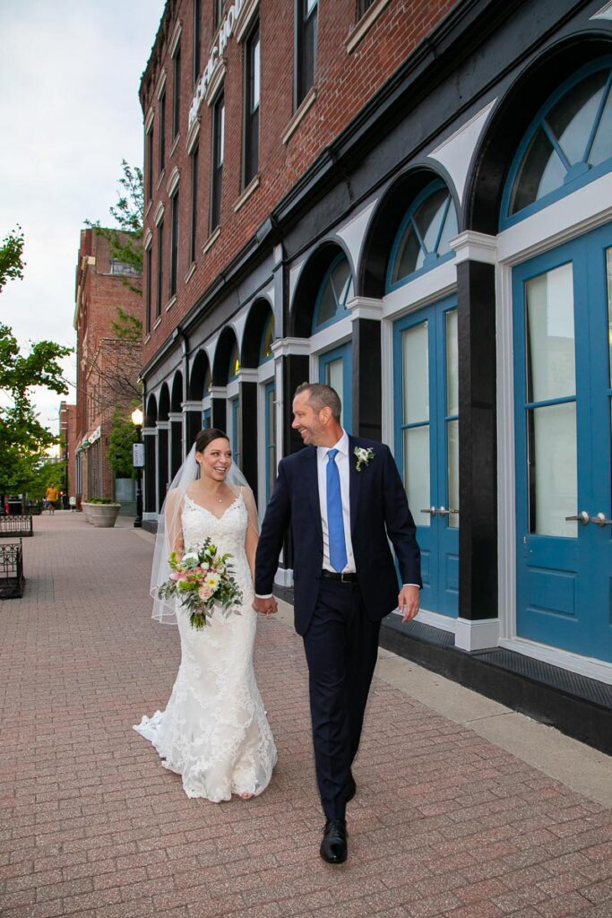 A bride and groom walking on a brick pavement