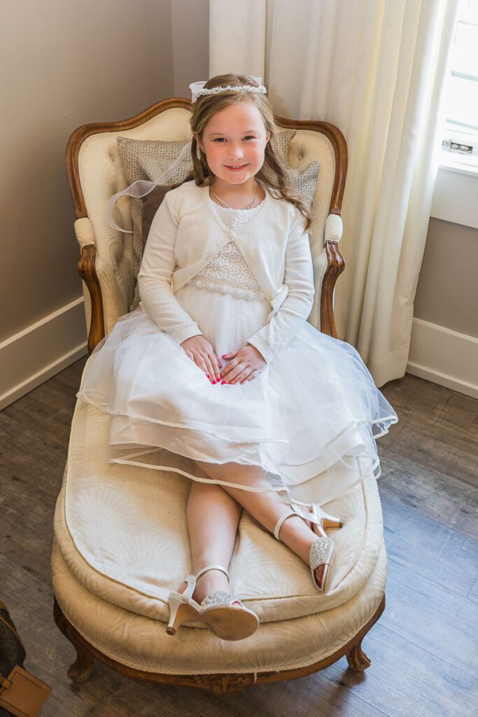 A little girl in white dress sitting on a sofa