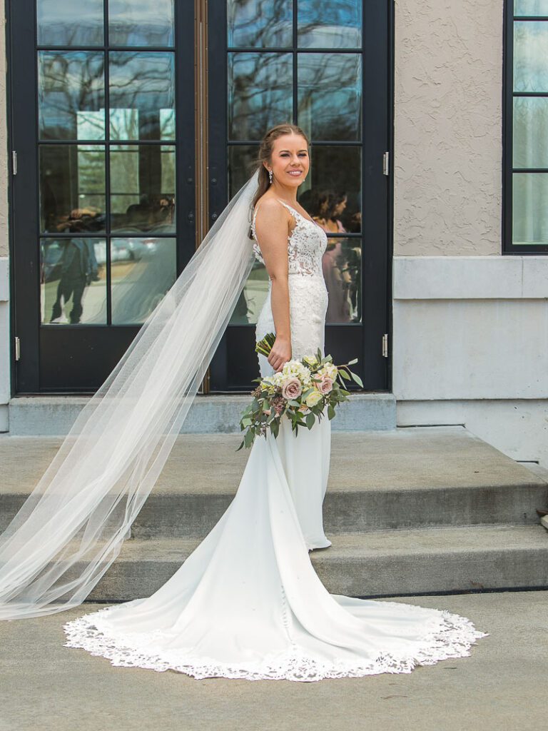 Bride posing with her wedding gown and bouquet