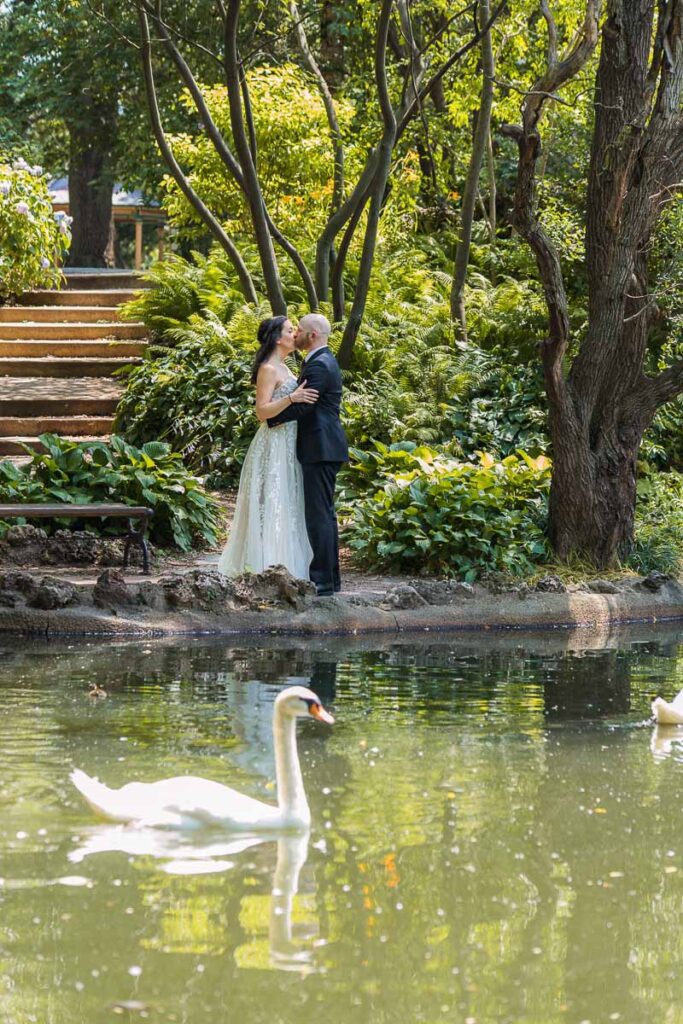 Bride and Groom standing and kissing each other near the pond