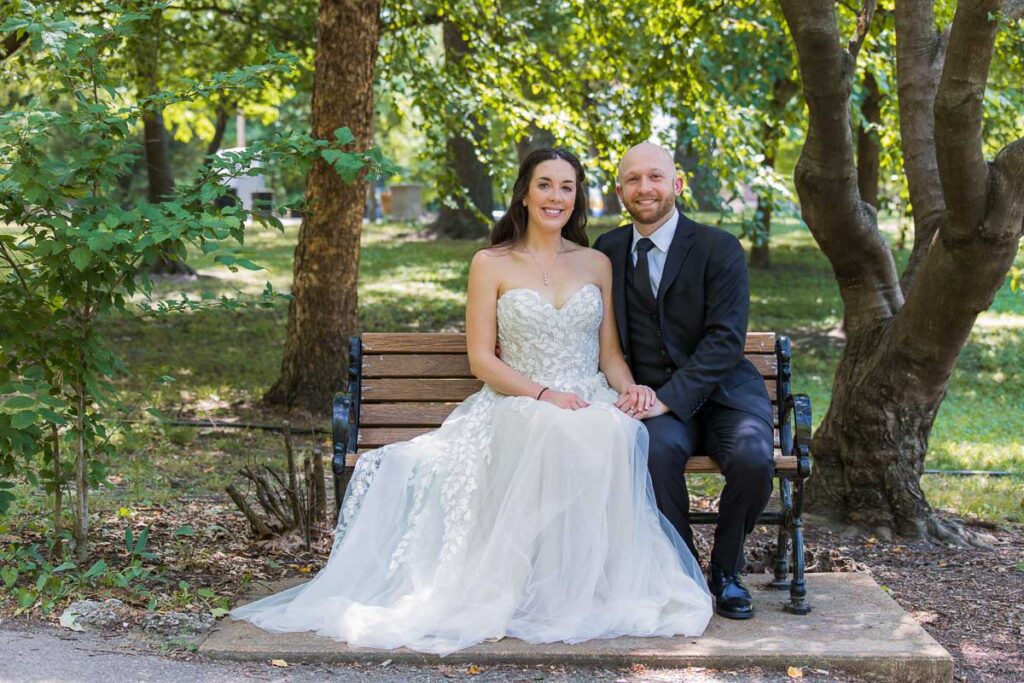 Bride and Groom holding hands and sitting on a bench