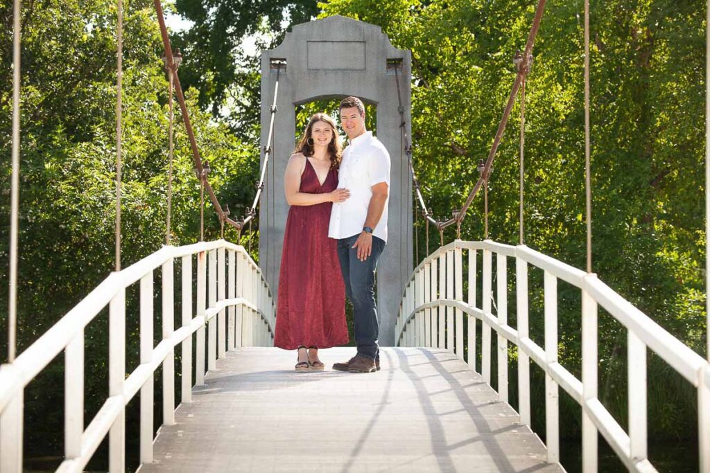 Couple standing in the middle of a bridge and smiling
