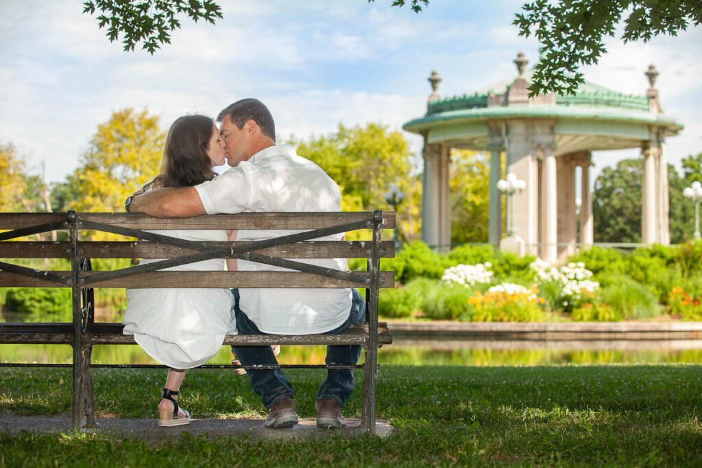 Couple in white dress sitting on bench and kissing each other