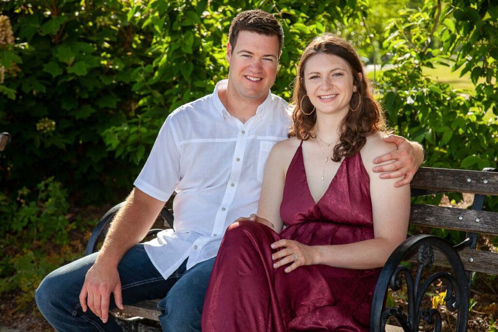 A close shot of Couple smiling and sitting on a bench in a park